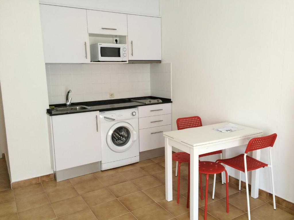 een keuken met een wasmachine en een tafel met stoelen bij Studio 88 - free Parking in Lloret de Mar