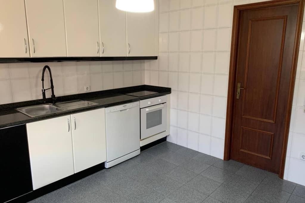 - une cuisine avec des placards blancs, un évier et une porte dans l'établissement Carminho beach house, à Vila do Conde