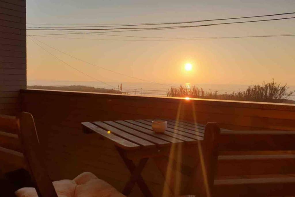 a table on a balcony with a sunset in the background at Carminho beach house in Vila do Conde