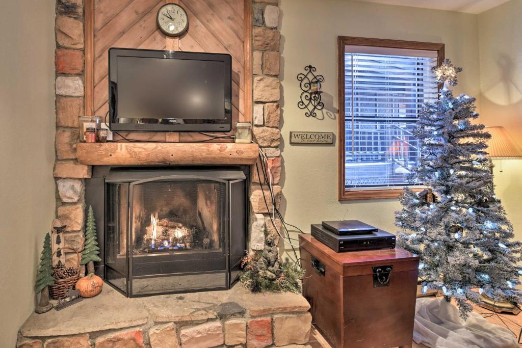 een woonkamer met een open haard, een televisie en een kerstboom bij Cozy Angel Fire Condo Less Than Half Mi to Resort! in Angel Fire