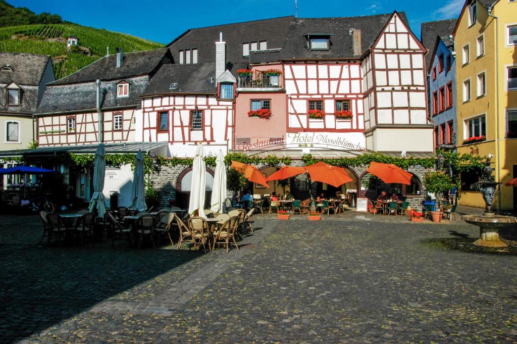 um grupo de edifícios com mesas e cadeiras em Hotel-Restaurant Moselblümchen em Bernkastel-Kues