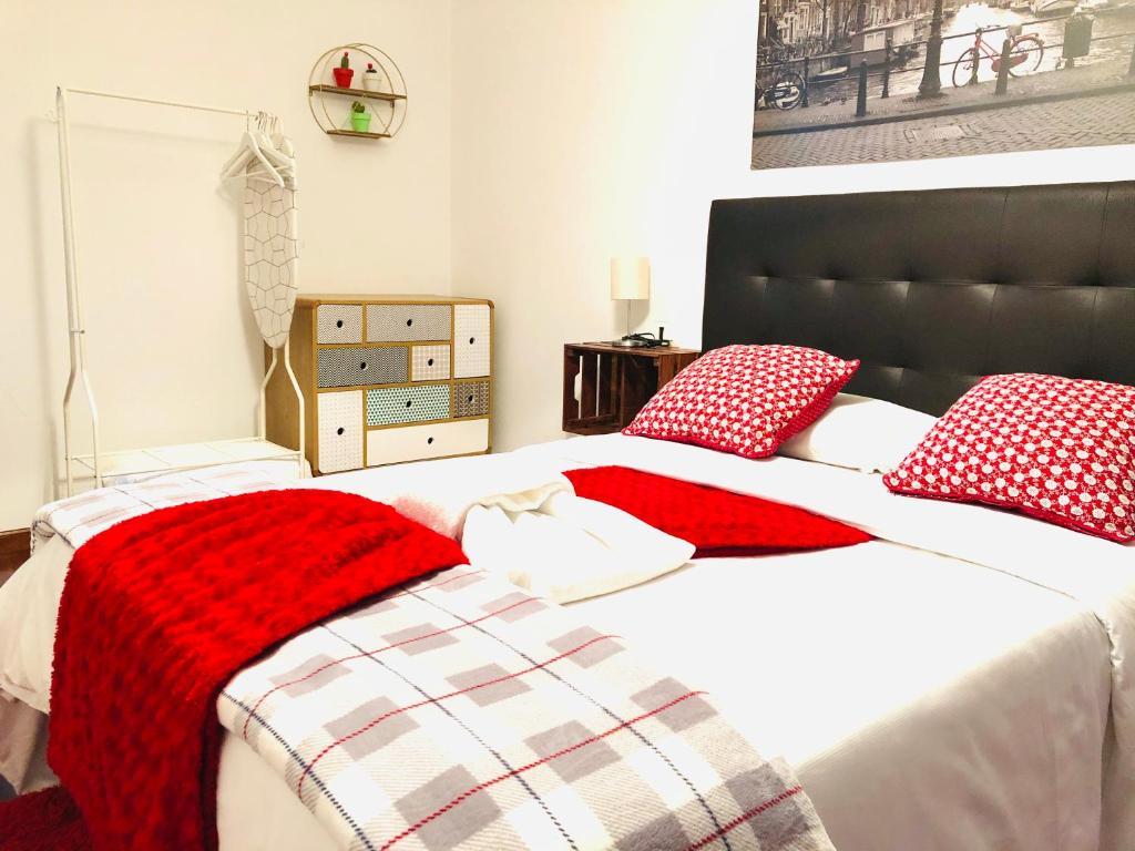 a bedroom with a bed with red and white pillows at O Faro Apartments in Ribadeo