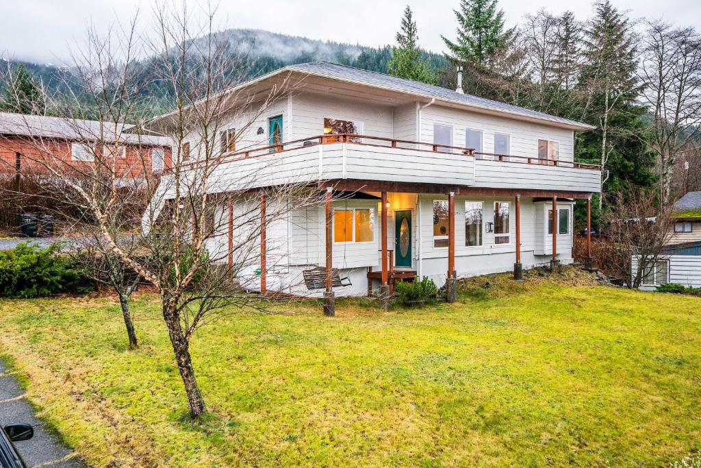 a white house with a dog sitting on the balcony at Ketchikan Home Bay Views, half Mi to Hiking Trails in Ketchikan