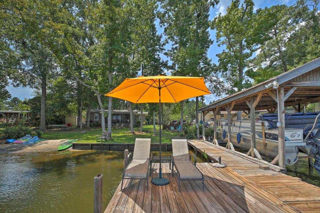 un ombrello arancione seduto su un molo accanto a una barca di Lake Sinclair Crooked Creek Cottage with Fire Pit! a Eatonton