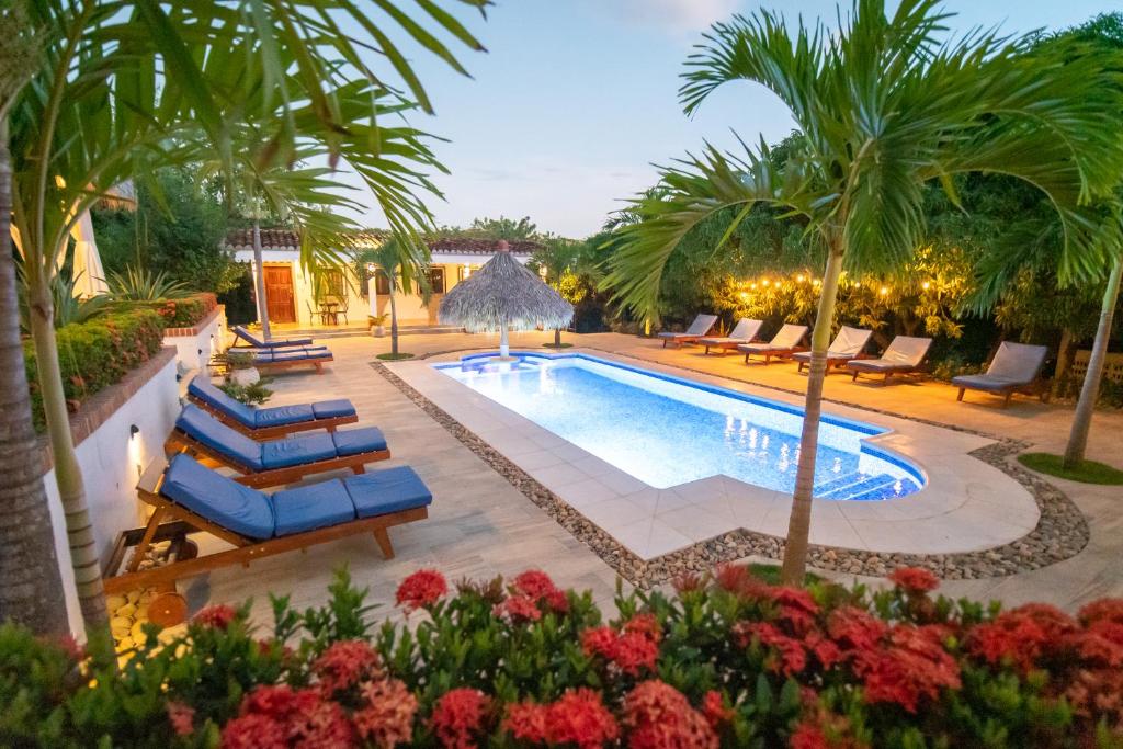 una piscina al aire libre con palmeras y tumbonas en Nicawaves, en Popoyo