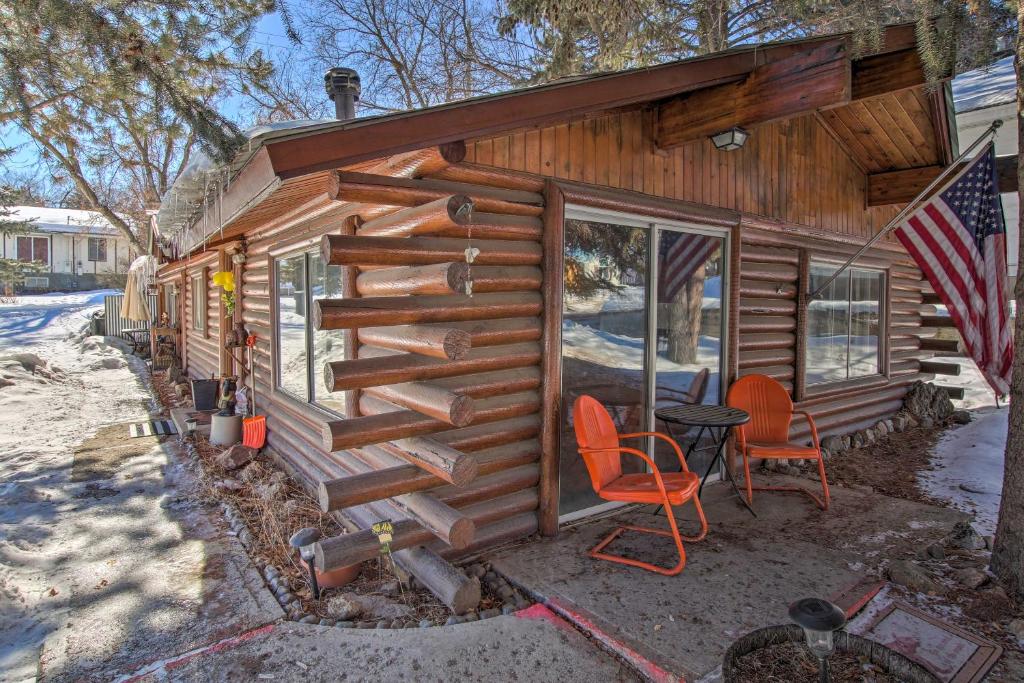 uma cabana de madeira com duas cadeiras e uma bandeira americana em Walk to Lava Hot Springs Pools from Cozy Cabin! em Lava Hot Springs