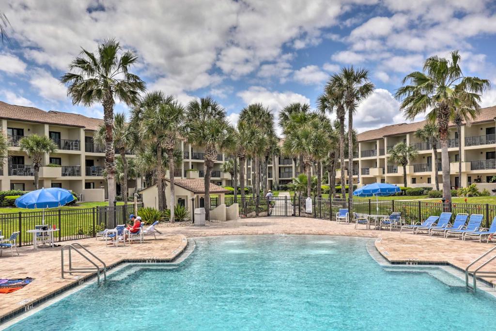 a pool with chairs and palm trees in front of a building at Beachside St Augustine Vacation Rental Condo! in Coquina Gables