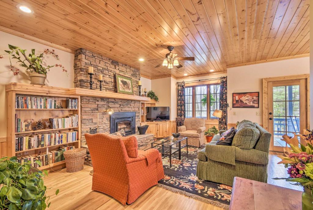 sala de estar con muebles y chimenea de piedra. en Trillium Links Condo with Deck Near Lake Glenville!, en Cashiers