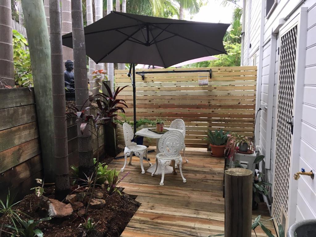 a patio with a table and chairs and an umbrella at Casuarina Studio in Yeppoon