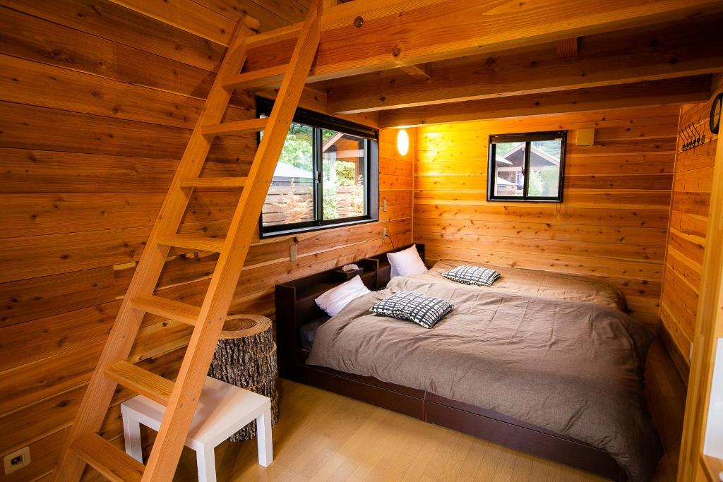 a bedroom in a log cabin with a bed and a ladder at SHIOYA SPA in Minakami