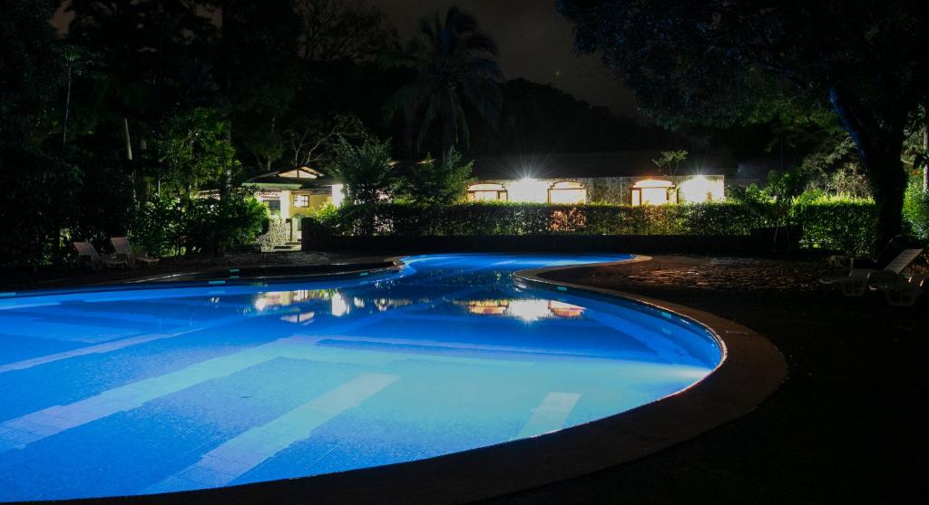 a large blue swimming pool in a yard at night at Malekus Mountain Lodge in Aguas Claras
