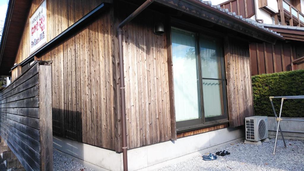 a house with a wooden wall and windows at 民泊和風一軒家貸し切り大人数にぴったりひろめ市場まで電車で15分の好立地 in Kochi