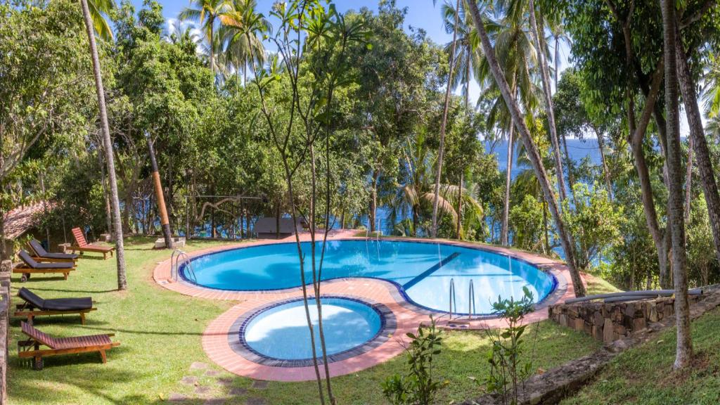 a swimming pool in the middle of a yard with trees at Palace Mirissa in Mirissa
