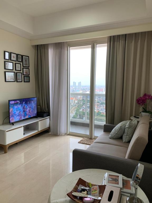 een woonkamer met een bank en een tv bij Menteng Park 19th in Jakarta