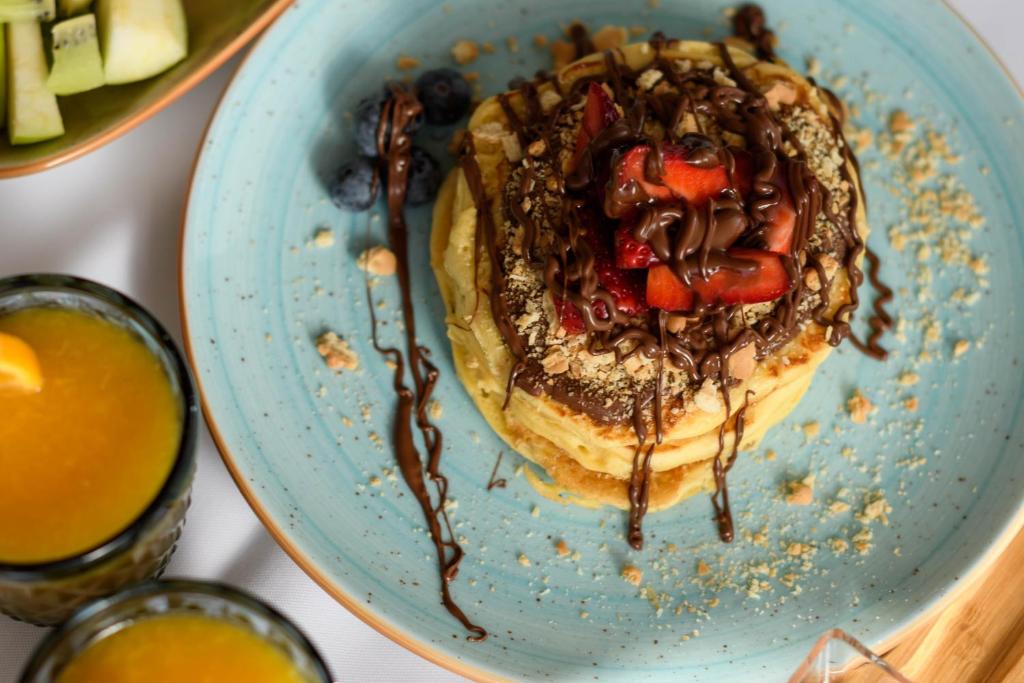 a plate of pancakes with fruit and chocolate sauce at Above Blue Suites in Imerovigli
