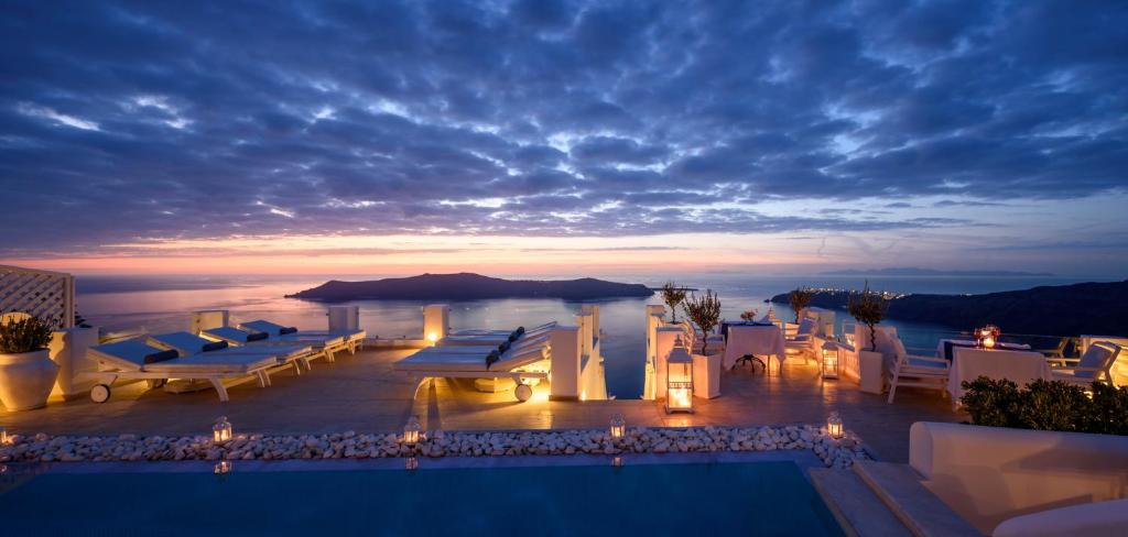 a view of a resort with a pool and a sunset at Above Blue Suites in Imerovigli