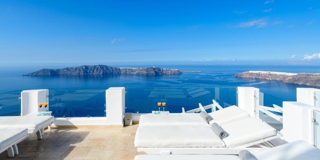 a room with white furniture and a view of the ocean at Above Blue Suites in Imerovigli