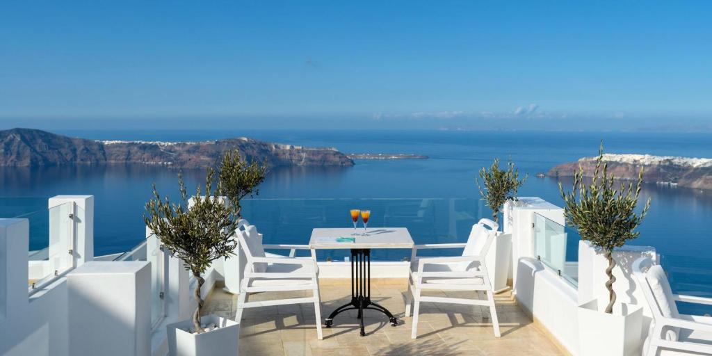 a table and chairs on a balcony overlooking the ocean at Above Blue Suites in Imerovigli