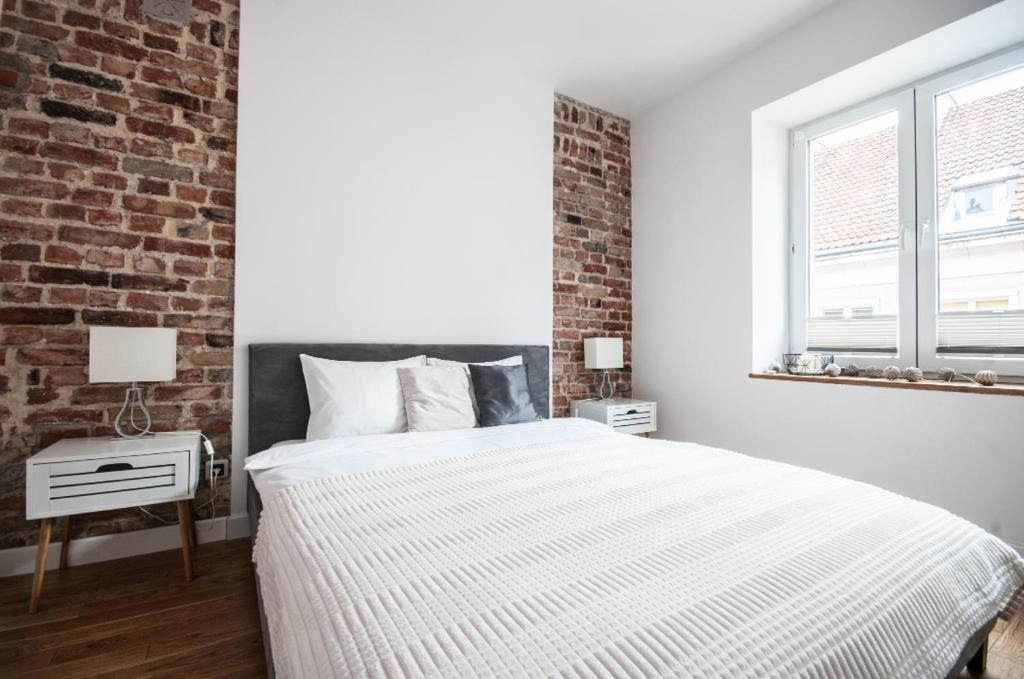 - une chambre avec un lit et un mur en briques dans l'établissement Apartament Bednarska Old Town, à Varsovie