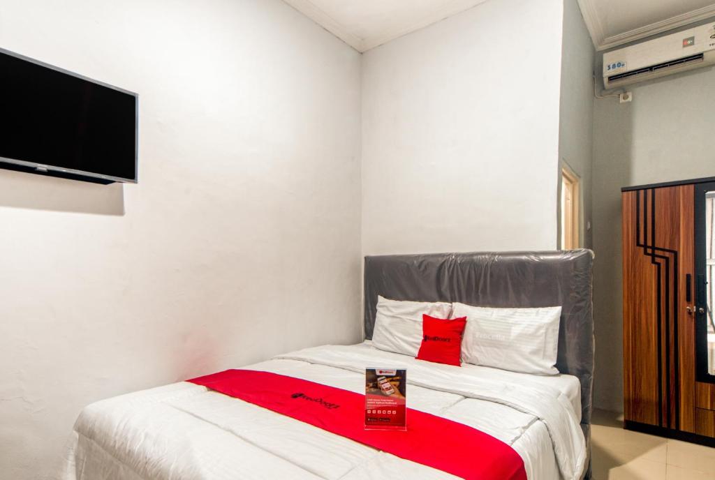 a bedroom with a bed with a red blanket at RedDoorz near Graha Cijantung Mall in Jakarta