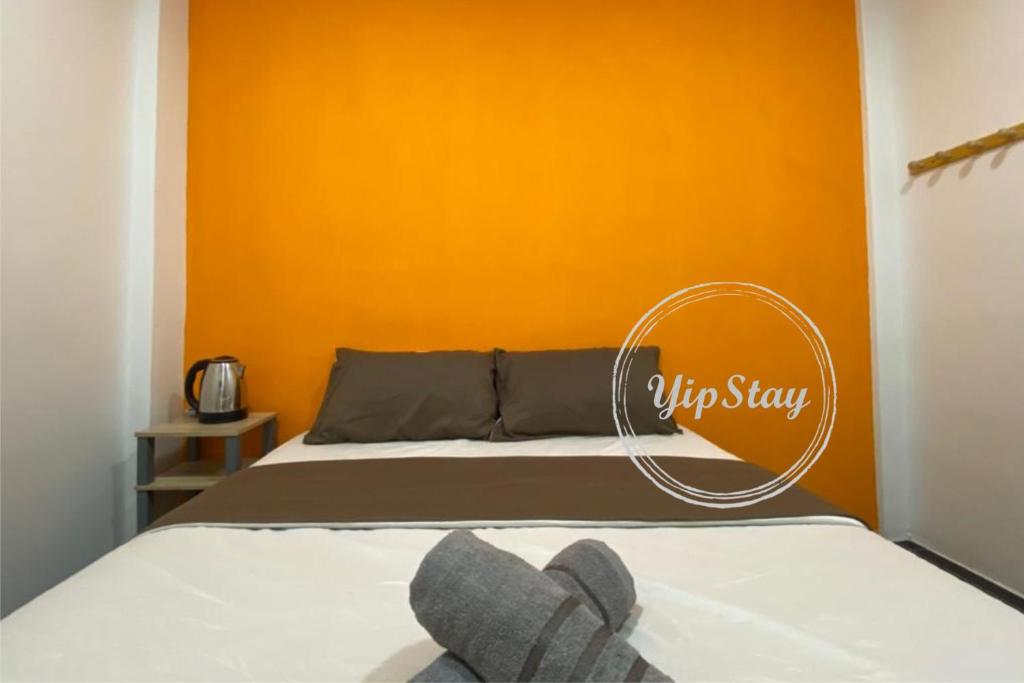 1 dormitorio con 1 cama con pared de color naranja en YipStay, en Gopeng