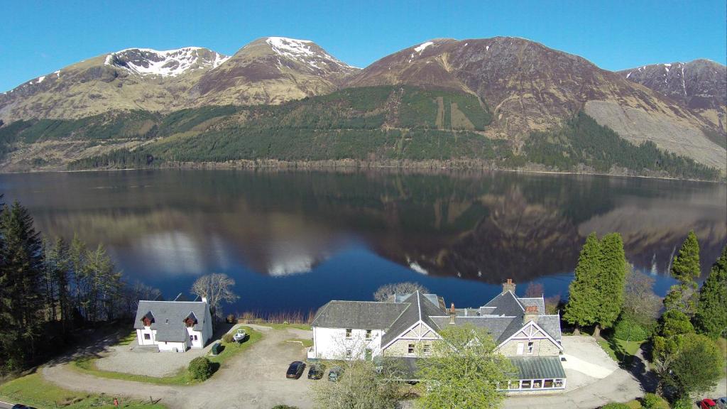 an aerial view of a house on a lake with mountains at Letterfinlay Lodge House in Letterfinlay