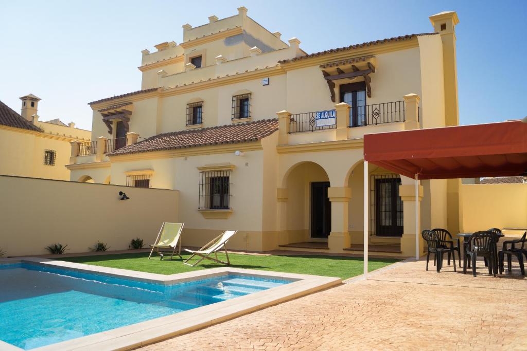 a villa with a swimming pool in front of a house at Casa de la Jara 10 in Sanlúcar de Barrameda