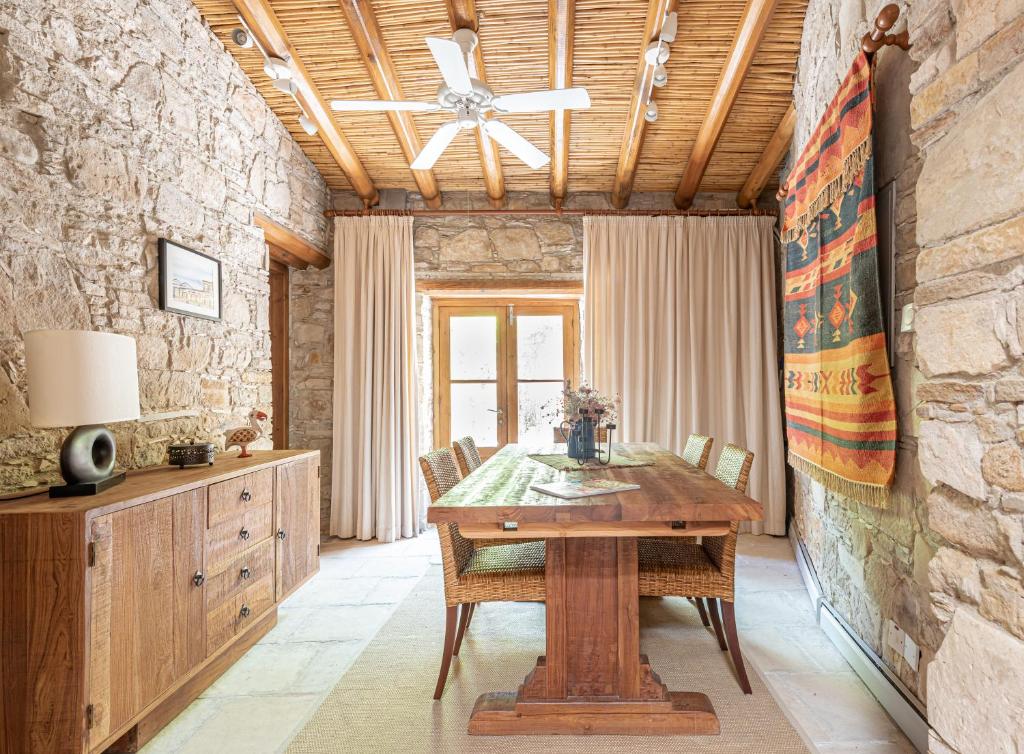 una sala da pranzo con tavolo in legno e parete in pietra di The Carob Tree Villa - 3 BR Rustic Luxury Home a Larnaka