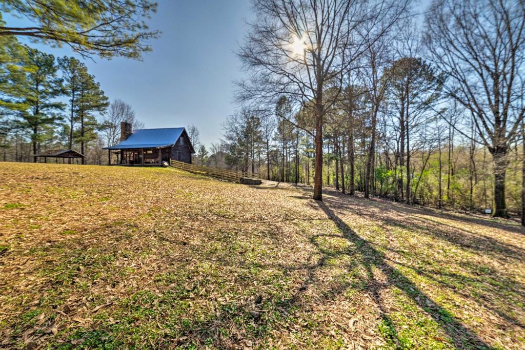 a house in the middle of a field with trees at Secluded Cabin with Fishing Pond near Hunting! in Bessemer