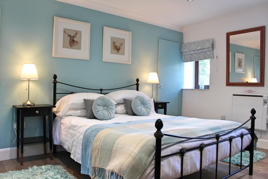 a bedroom with a bed with blue walls at Cobbler's Cottage in Dunblane