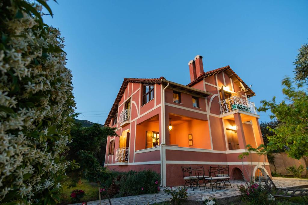 a large orange house with a porch and balcony at Beachfront Villa Meliti in Ágios Matthaíos