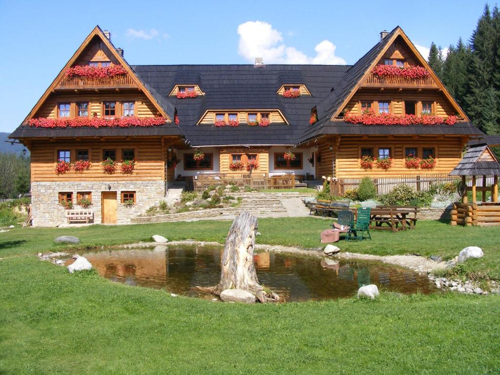 a log house with a pond in front of it at Wellness Penzion u Michala in Zuberec