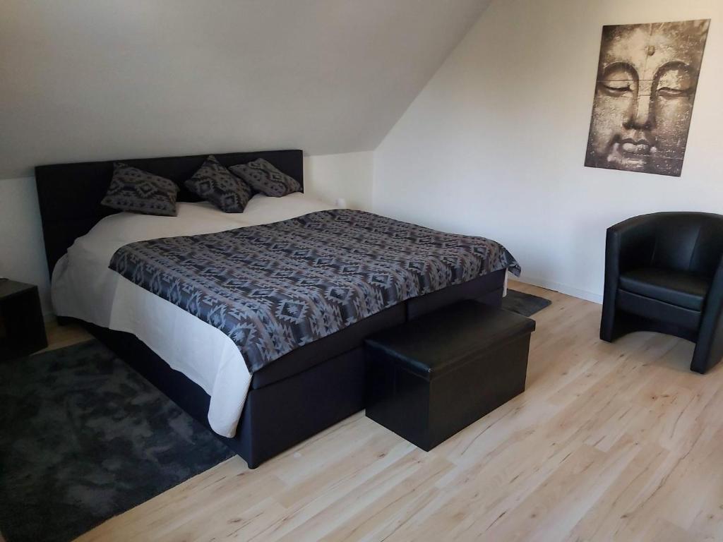 a bedroom with a bed and a black chair at Top-Apartment in Isernhagen