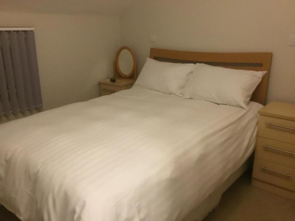 a bedroom with a white bed with a wooden headboard and a mirror at The Loco in Doncaster