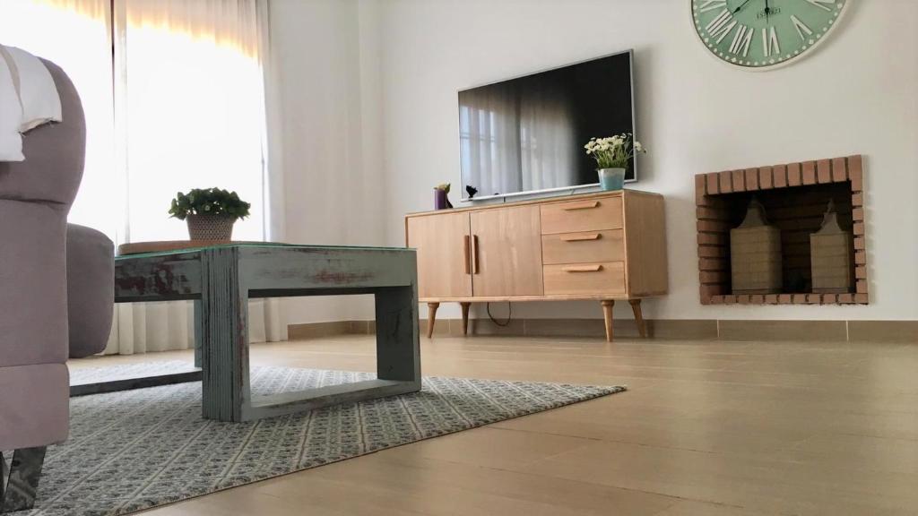 salon ze stołem, komodą i zegarem w obiekcie Casa de la Jara 10 w mieście Sanlúcar de Barrameda