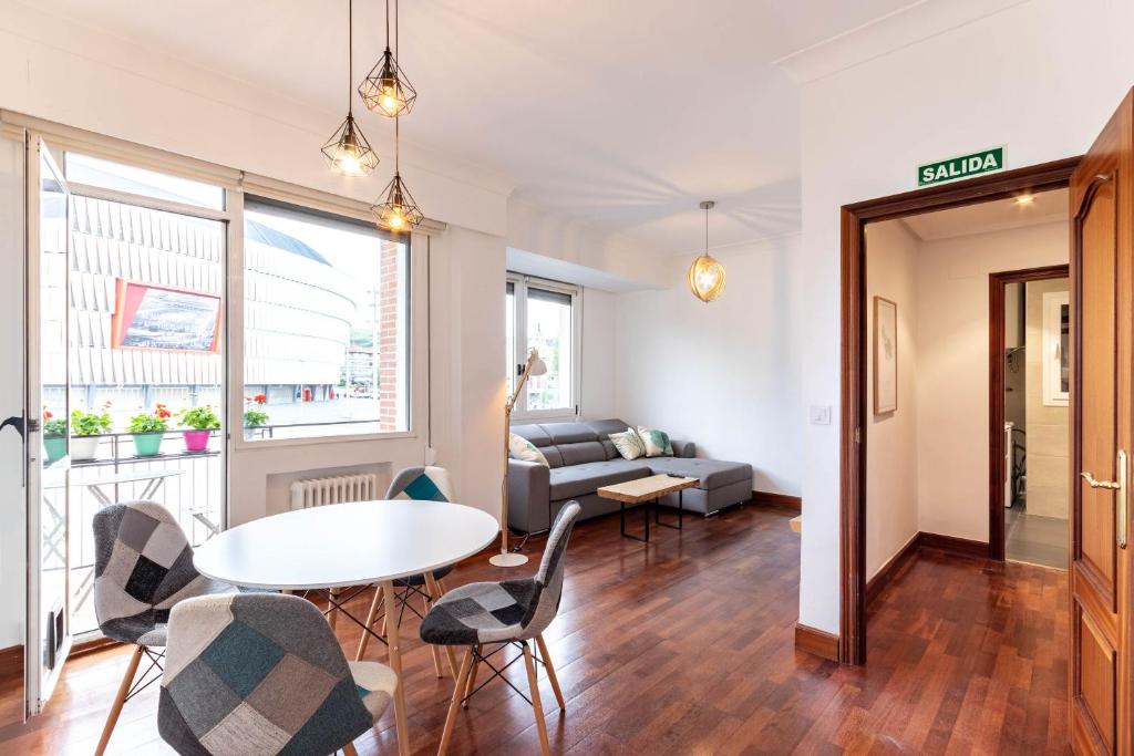 uma sala de estar com uma mesa e cadeiras e um sofá em Apartamento con vistas al Estadio San Mamés em Bilbau