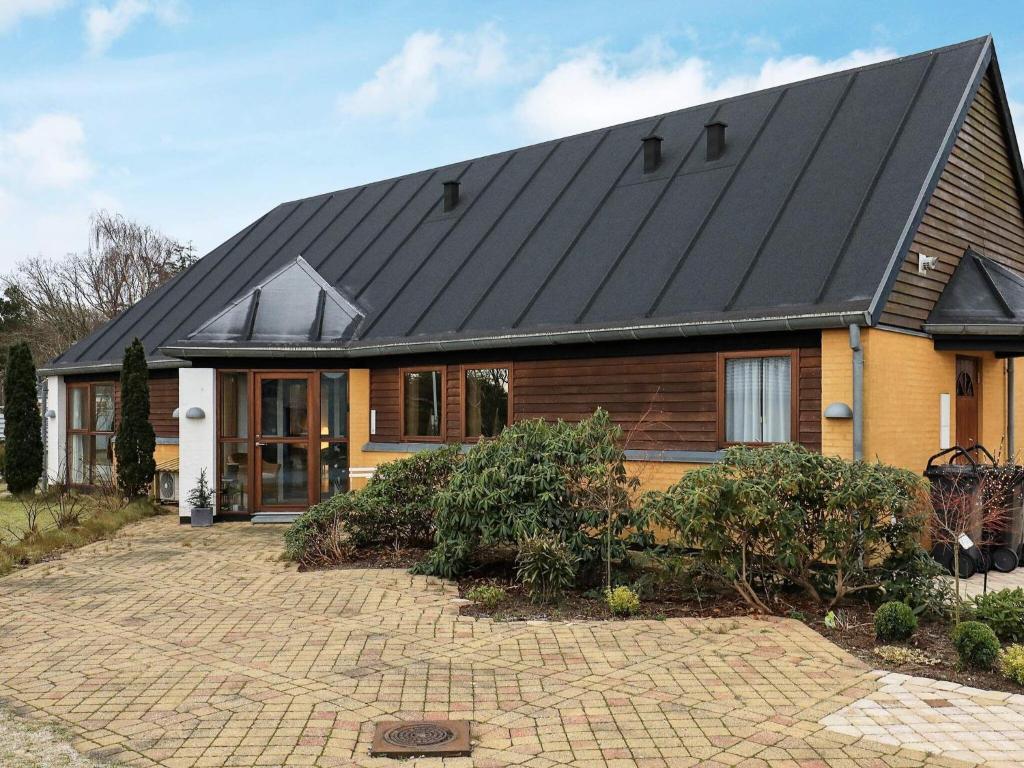 a house with a black roof on a brick driveway at 8 person holiday home in Skagen in Skagen