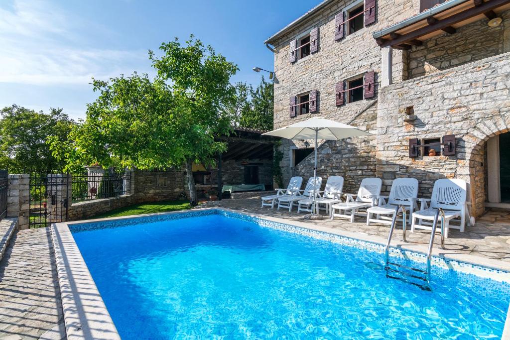 una piscina con sillas y una sombrilla junto a un edificio en Villa Maria, en Oprtalj