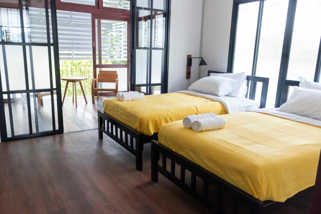 a bedroom with two beds with yellow sheets and a table at liaw base house in Bangkok