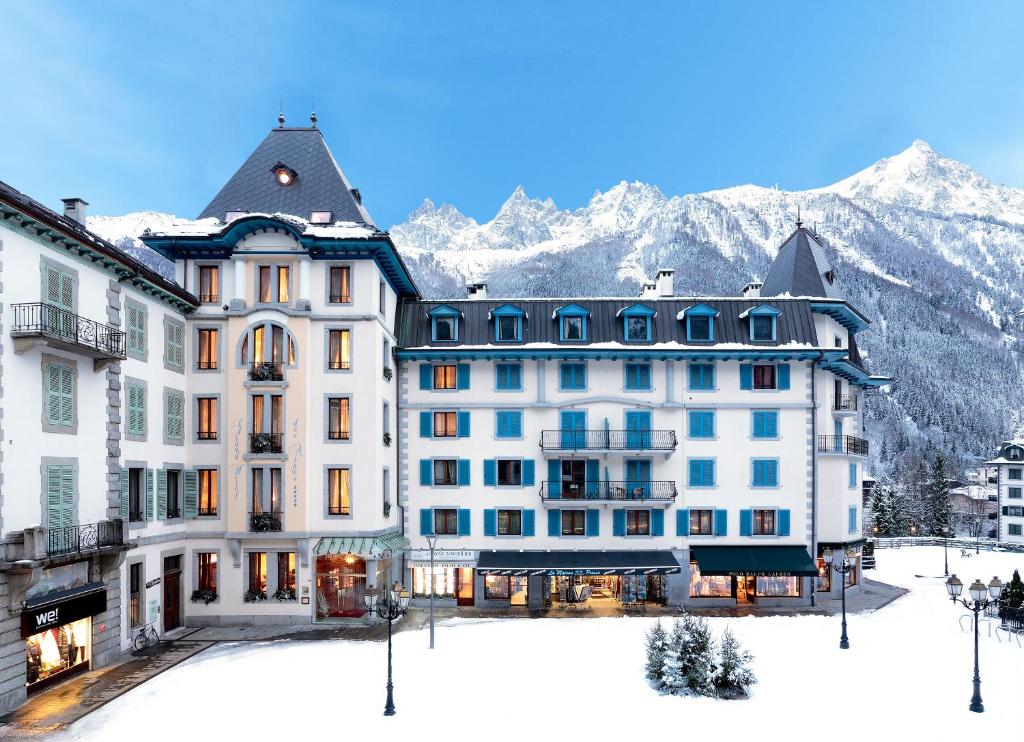 un hôtel dans la neige avec des montagnes en arrière-plan dans l'établissement Grand Hôtel des Alpes, à Chamonix-Mont-Blanc
