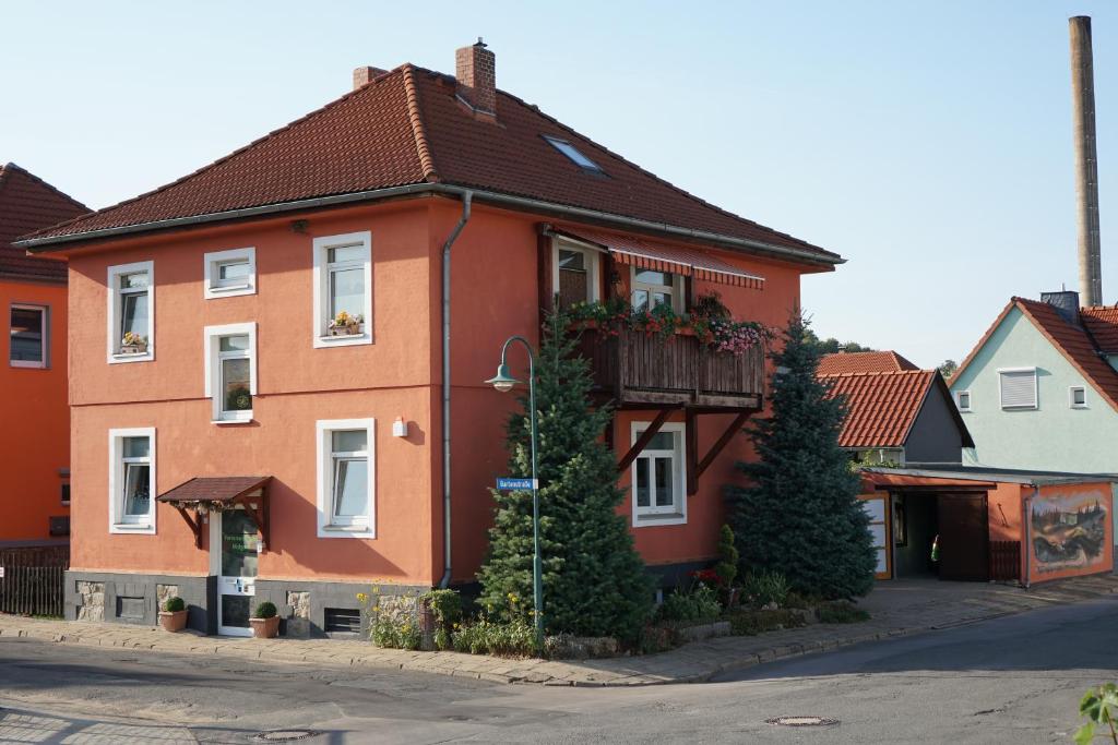 ein rotes Haus mit Balkon auf einer Straße in der Unterkunft Ferienwohnung Midgard in Thale