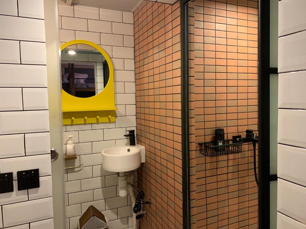 a bathroom with a sink and a yellow mirror at Wontonmeen in Hong Kong