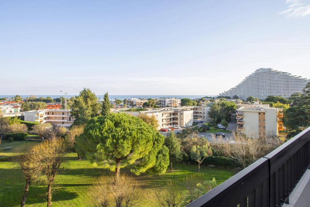- un balcon donnant sur un parc arboré et des bâtiments dans l'établissement Appartement Panorama - Welkeys, à Villeneuve-Loubet