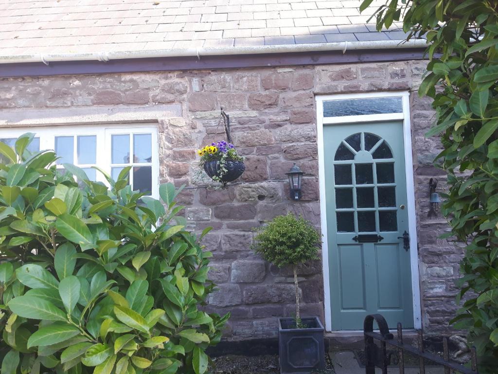 a stone house with a blue door and two windows at The Snug in Goodrich