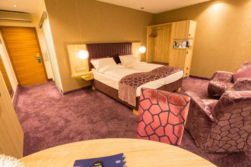a hotel room with a bed and a couch and chairs at Top Hotel Hammer - KLIMATISIERT Mainz Hauptbahnhof in Mainz