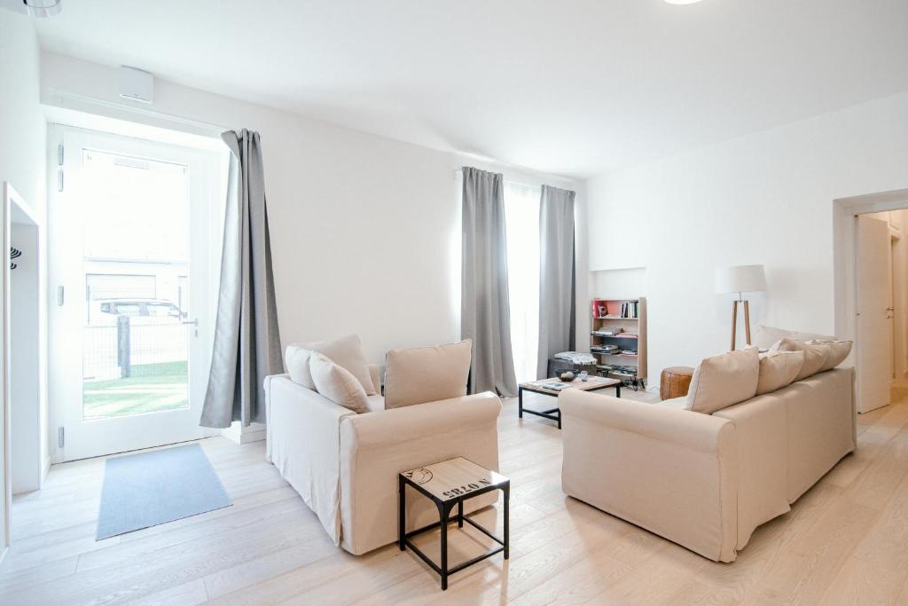 ein Wohnzimmer mit zwei weißen Sofas und einem Fenster in der Unterkunft Borgovico Garden - The House Of Travelers in Como