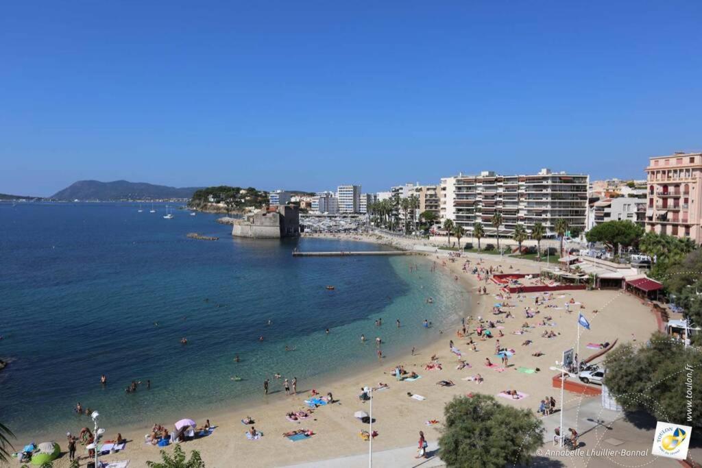 eine Gruppe von Menschen an einem Strand in der Nähe des Wassers in der Unterkunft Bel appartement T3 Mourillon à 5 min des Plages - vue mer in Toulon