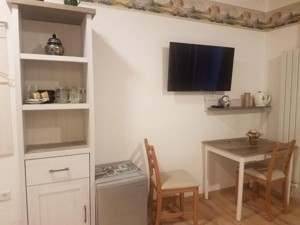 a dining room with a table and a tv on the wall at Ferienwohnung Wacker, Apartments und Zimmer in Züschen