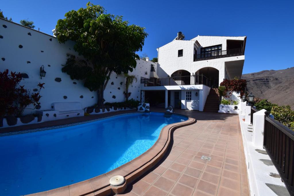 a villa with a swimming pool in front of a house at Villa Altos de Santiago in Playa de Santiago