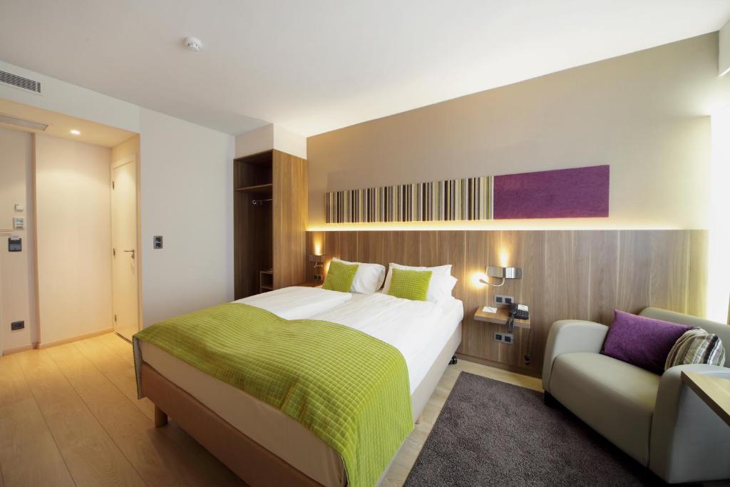 ブリュッセルにあるHoliday Inn Brussels Schuman, an IHG Hotelのベッドルーム(大型ベッド1台、ソファ付)